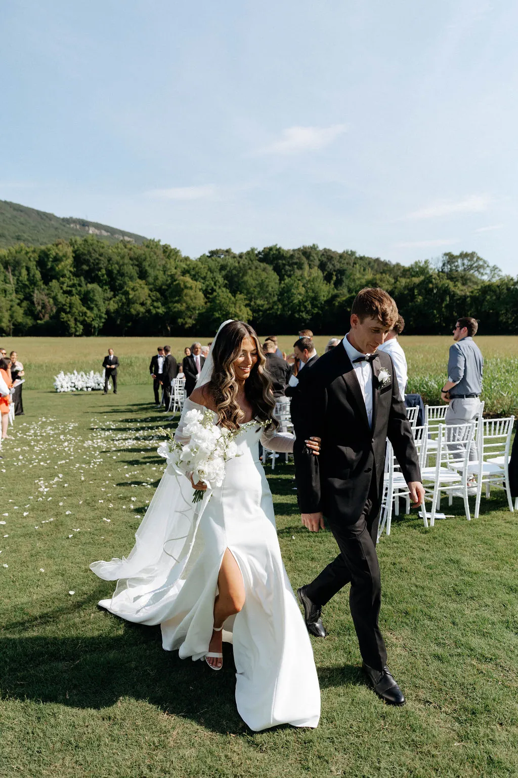 A bride and groom walking back up the aisle in the meadow