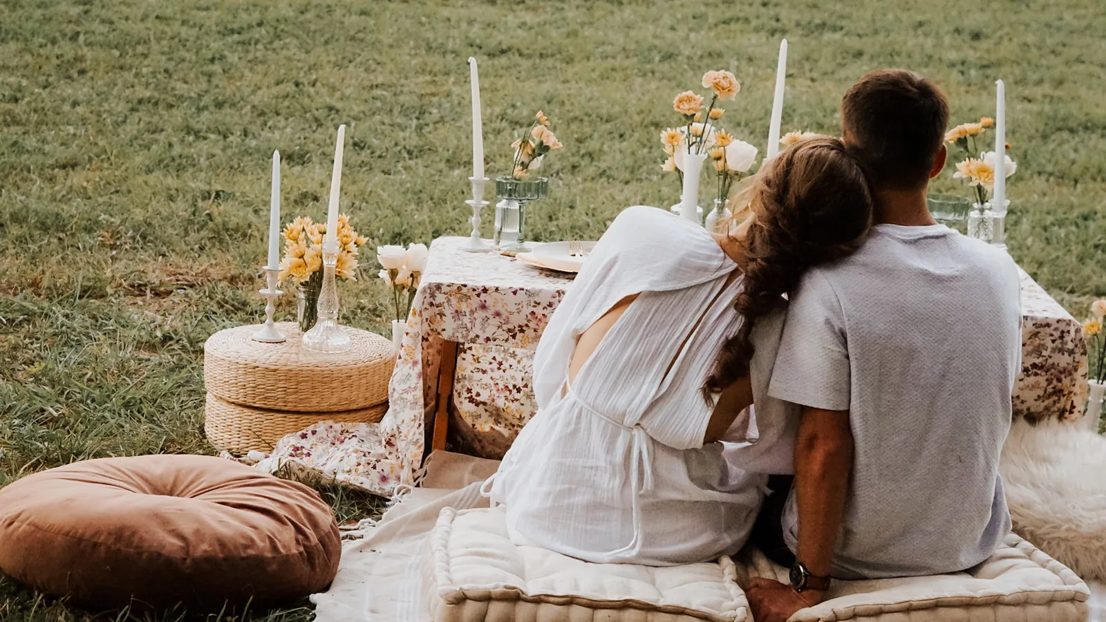 A couple at a picnic breakfast laid in the meadow