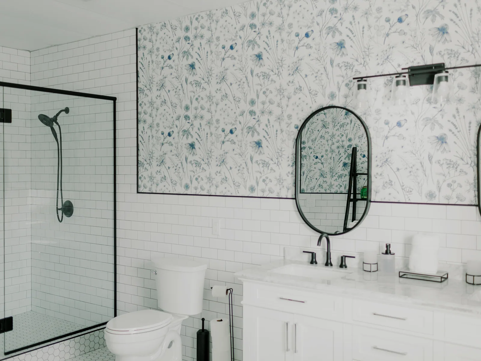 A bathroom: twin mirrors, white tile and a walk-in shower