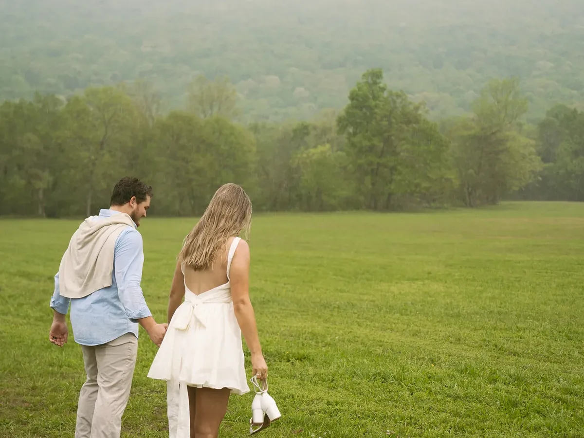 A couple walking hand in hand across the misty meadow the next morning