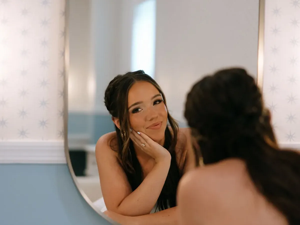 A bride smiling into the mirror of the getting ready suite